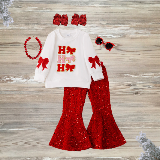 Coquette-style girls' white Christmas top with "Ho Ho Ho" lettering and bows, paired with red sequin bell bottom pants, girls chirstmas red sequin outfit, girls boutique clothing, sequin pants christmas outfit