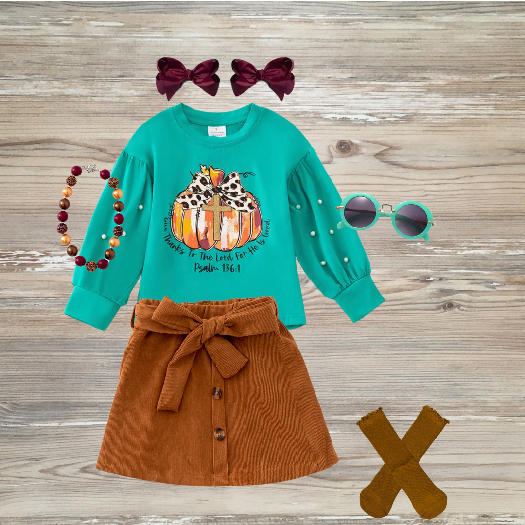 Teal girls' long sleeve top with pumpkin and cross graphic, leopard-print bow, pearl sleeve detail, and Psalm 136:1 scripture. Girl's boutique fashion top for holidays, thanksgiving, christian clothing give thanks to the lord