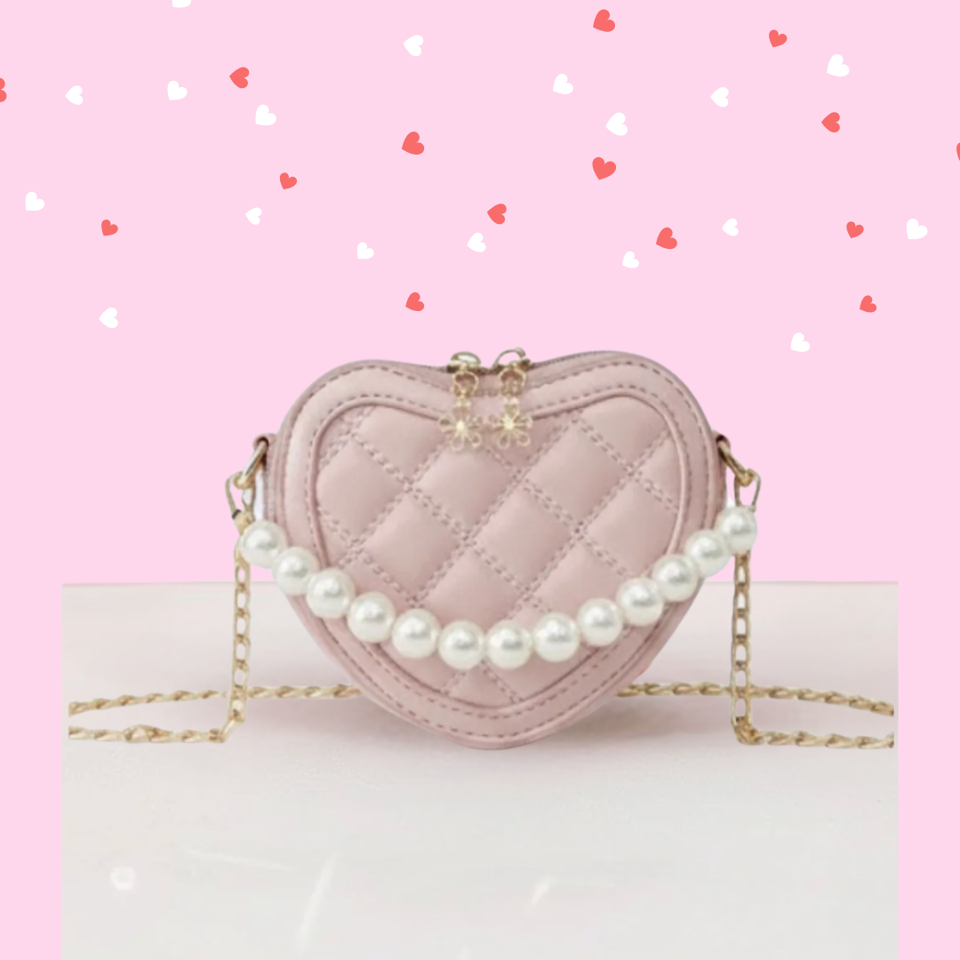 A pink heart-shaped kids' handbag with a quilted pattern and a decorative white pearl handle. girl's heart shaped purse for valentine's online boutique handbags and purses for babies and kids pink heart purse, girl's crossbody purse, hanbags and purses for toddlers, girl's vegan leather purses, vegan leather handbag kids