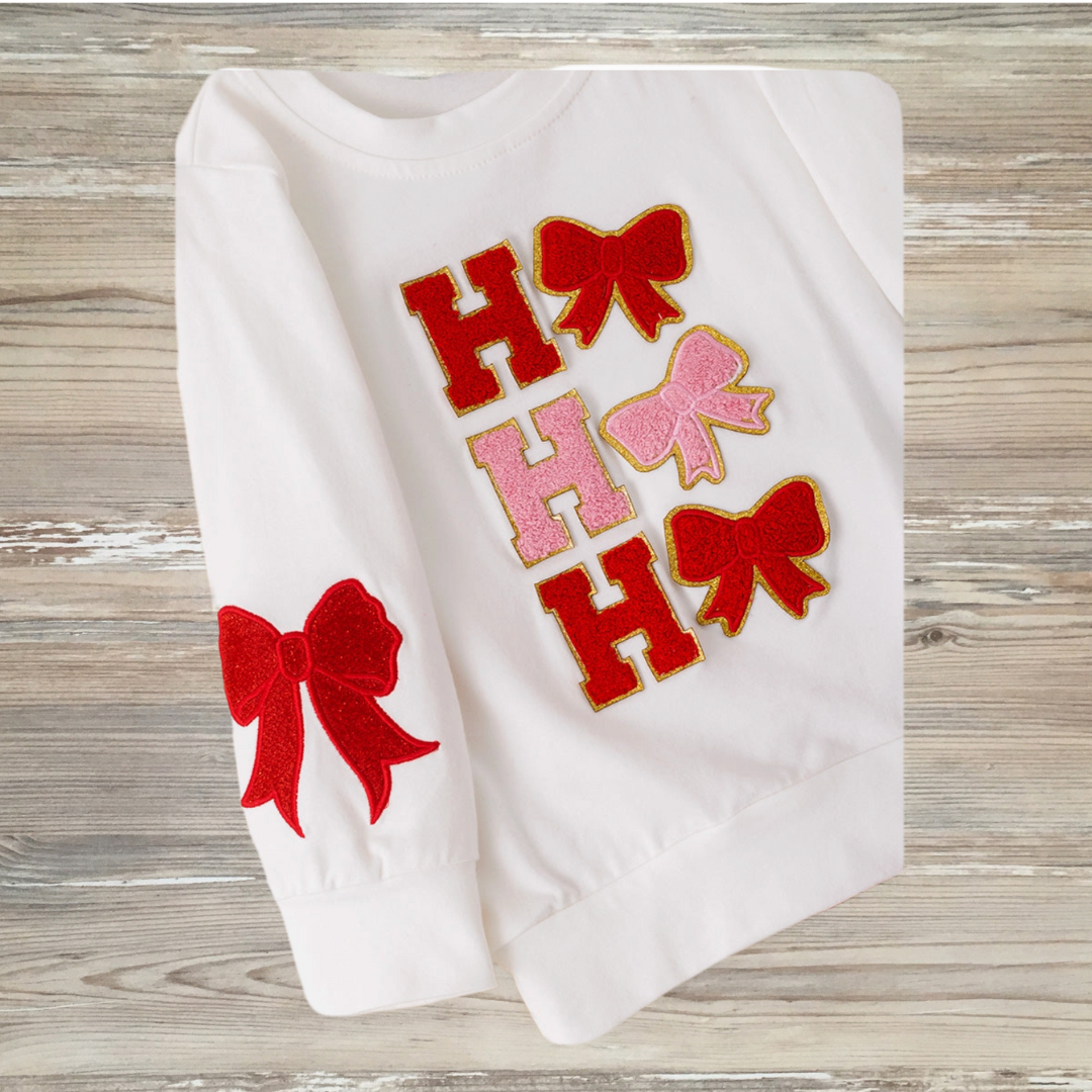 Coquette-style girls' white Christmas top with "Ho Ho Ho" lettering and bows, paired with red sequin bell bottom pants, girls chirstmas red sequin outfit, girls boutique clothing, sequin pants christmas outfit