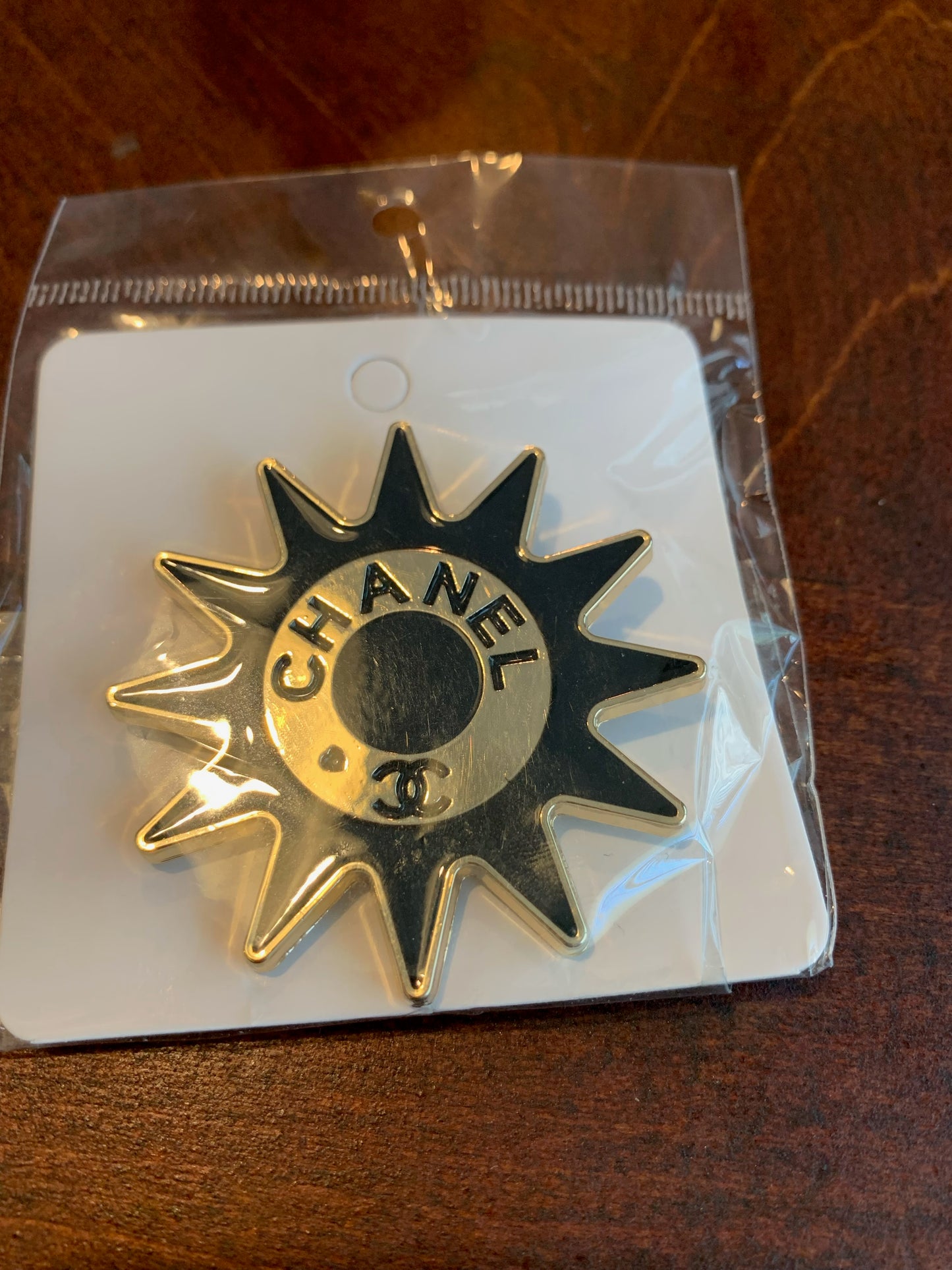 A Chanel 33 starburst-shaped metal pin in silver,  chanel inspired brooches, black and gold