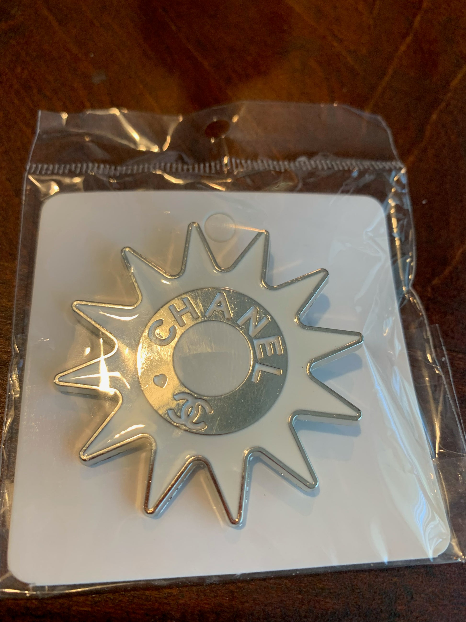 A Chanel 33 starburst-shaped metal pin in silver,  chanel inspired brooches, white and silver