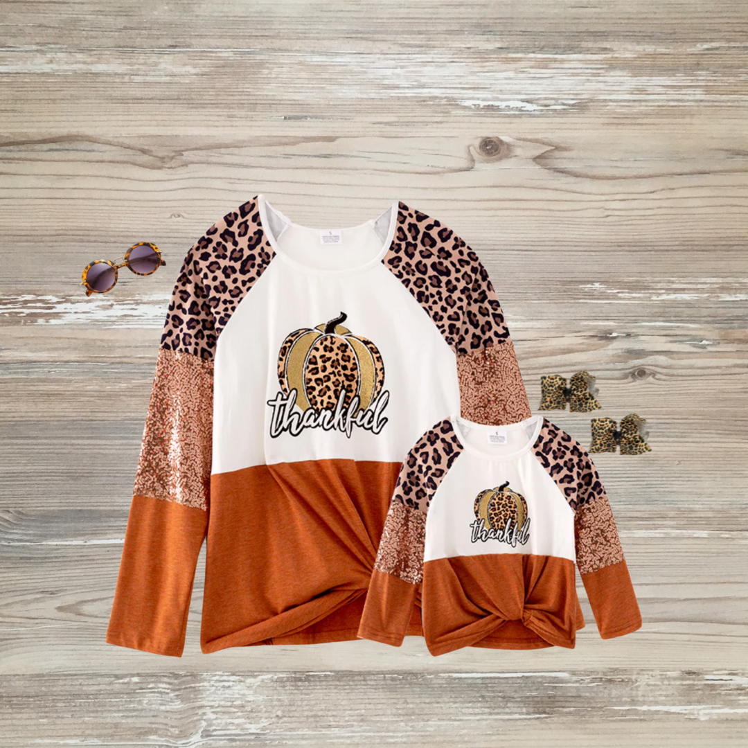 mommy and me dresses, mommy and me clothes, mom and me matching clothes, mommy and me fashion, mommy and me outfits, mommy and me style thankful, thankgiving, Matching “Thankful” mama and mini long-sleeve tops with leopard pumpkin graphic, sequin and leopard print sleeves, and rust-orange color block, perfect for fall and Thanksgiving family outfits.