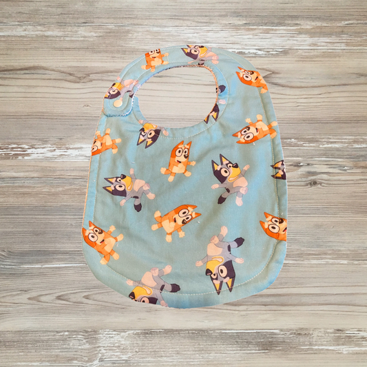 Blue adaptive bib for children with special needs or drooling, featuring Bluey and Bingo cartoon characters on a light blue background