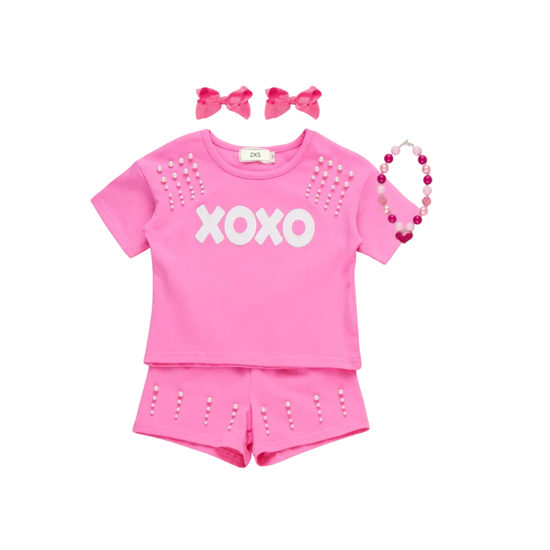 A matching Mommy and Me Valentine's Day outfit set in hot pink. The set features short-sleeve t-shirts with "XOXO" in white text and pearl studs on the shoulders, paired with matching pink shorts with pearl details. online boutique mommy and me outfit, mama and me outfit, mama and mini outfit, girls valentine's day outfit