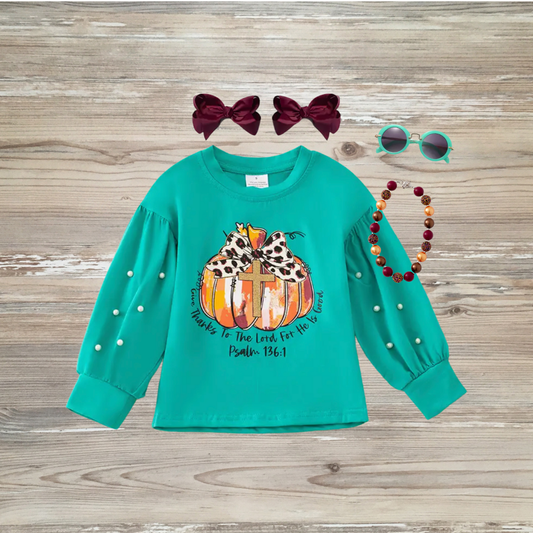 girl's long sleeve top with pumpkin and cross graphic, leopard-print bow, pearl sleeve detail, and Psalm 136:1 scripture. Girl's boutique fashion top for holidays, thanksgiving, christian clothing give thanks to the lord, girl's thanksgiving top shirt trending trendy, kids online boutique