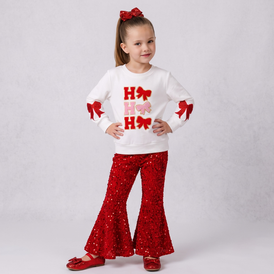Coquette-style girls' white Christmas top with "Ho Ho Ho" lettering and bows, paired with red sequin bell bottom pants, girls chirstmas red sequin outfit, girls boutique clothing, sequin pants christmas outfit